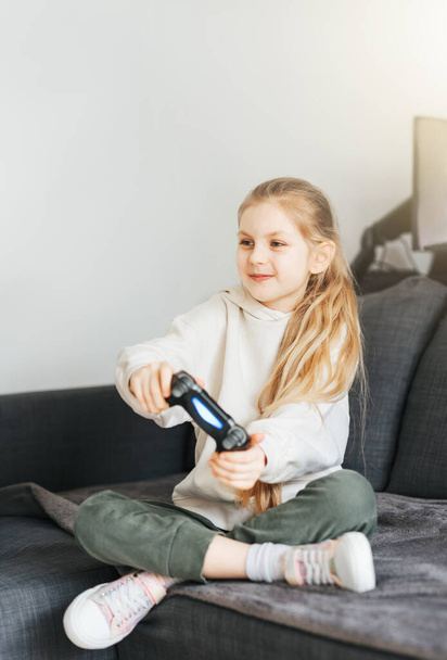 A little girl holding game controller playing video games - Photo, Image