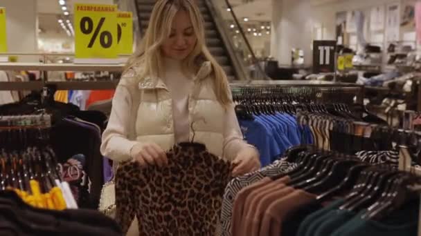 Ευτυχισμένη νεαρή γυναίκα που αγοράζει καινούργια ρούχα. Πώληση μόδας ψώνια και οι άνθρωποι έννοια.  - Πλάνα, βίντεο