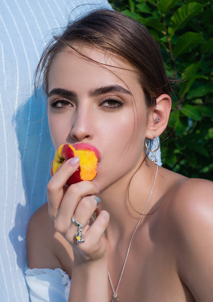 Porträt einer jungen spanischen Frau im Freien. Frau isst Pfirsich, aus nächster Nähe. Landmädchen mit Pfirsich aus nächster Nähe. Nahaufnahme Frau Gesicht essen Pfirsich in der Natur - Foto, Bild