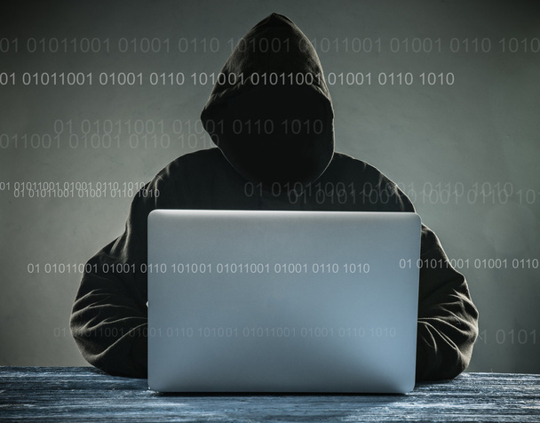 A hacker with a hood with laptop - Photo, Image