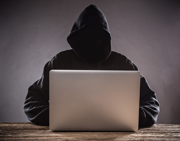 Un hacker con capucha con portátil
 - Foto, imagen
