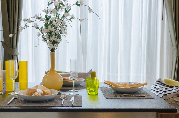 Желтая ваза с цветами на деревянном столе в столовой
  - Фото, изображение