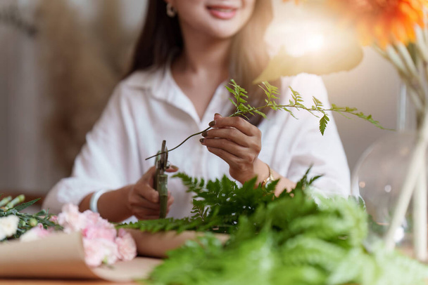 Startup, small business, flower shop. Young pretty florist putting a flower on a vase. - Foto, Imagem