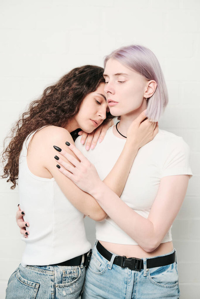 Calm young Caucasian lesbians in white tshirts touching each other while embracing - Φωτογραφία, εικόνα