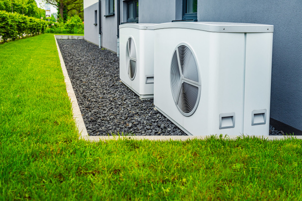 Zwei Luftquellen-Wärmepumpen außerhalb des neuen und modernen Stadthauses installiert, Konzept der grünen erneuerbaren Energien der Wärmepumpe - Foto, Bild
