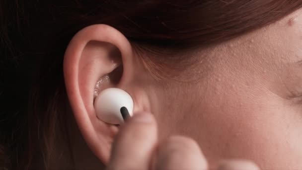 mujer joven escuchando música usando auriculares inalámbricos modernos, primer plano - Metraje, vídeo