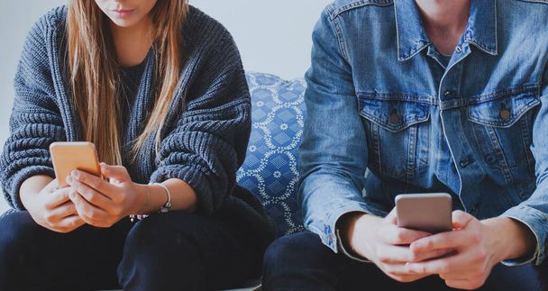 internet and social network addiction, man and woman holding smartphones while sitting together, problem of virtual communication - Zdjęcie, obraz
