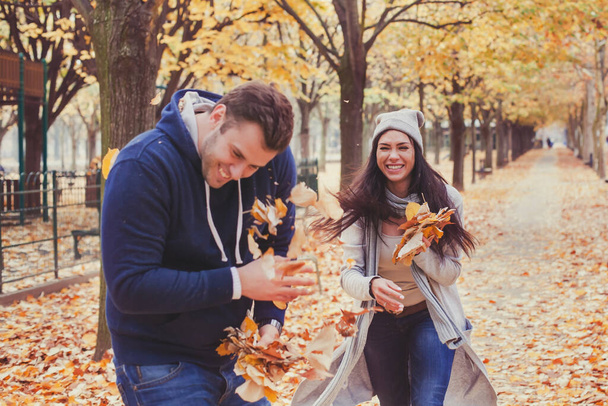 Couple having fun in autumn park. Happy people in fall season. - Zdjęcie, obraz