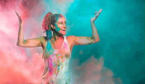 Gökkuşağı renkli tozla kaplı tasasız neşeli kadın renk festivalini kutluyor. Genç kadın renkli holi pudrasıyla eğleniyor.. - Fotoğraf, Görsel