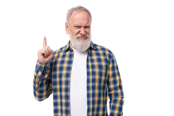 well-groomed 60s middle-aged gray-haired retired man with a mustache and beard points with a finger at the empty space of the wall. - Photo, Image