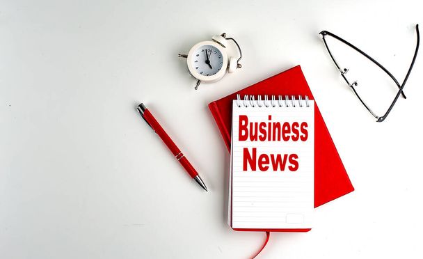 BUSINESS NEWS text on a notebook , red pen and notebook, business concept, white background - Fotó, kép
