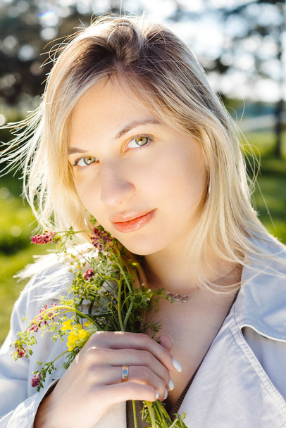 Estilo de vida de primavera retrato de la hermosa mujer joven sonriendo y sosteniendo ramo de flores silvestres. Concepto de felicidad y amor. - Foto, Imagen