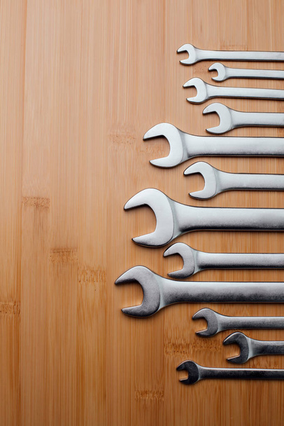 A set of working tools, different size wrenches on a brown wooden, bamboo background. Top view - Valokuva, kuva