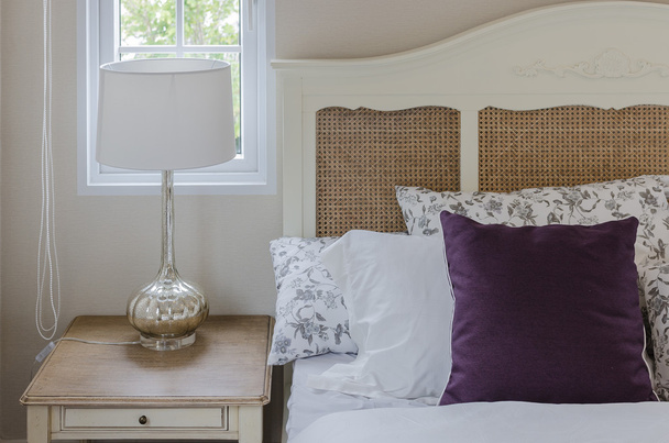 фиолетовая подушка на деревянной кровати с лампой в спальне
 - Фото, изображение
