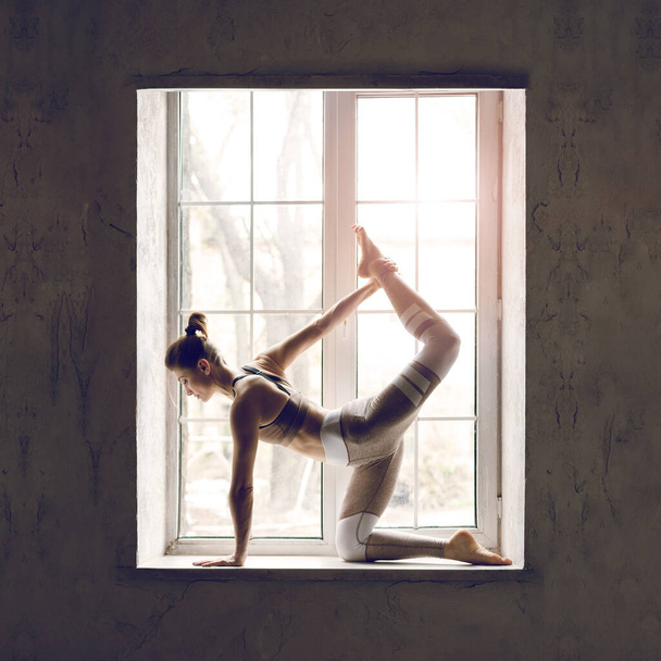 Atrakcyjne Sporty Młoda kaukaska kobieta robi ćwiczenia przeciwko oknie. - Zdjęcie, obraz
