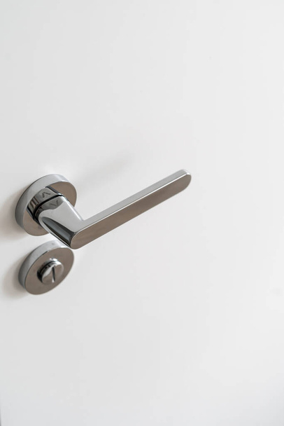High angle view of aluminum doorknob and lock on the white door. Concept of secrecy and protection. Interior design of modern room. Copy space - Photo, Image