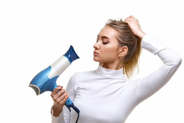 Portrait of attractive cheerful girl holding hair dryer isolated on white background - Foto, Imagen