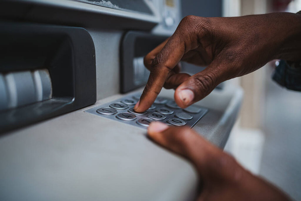 Primer plano de un hombre escribiendo su código PIN en un teclado de un cajero automático para retirar dinero del banco - Foto, Imagen
