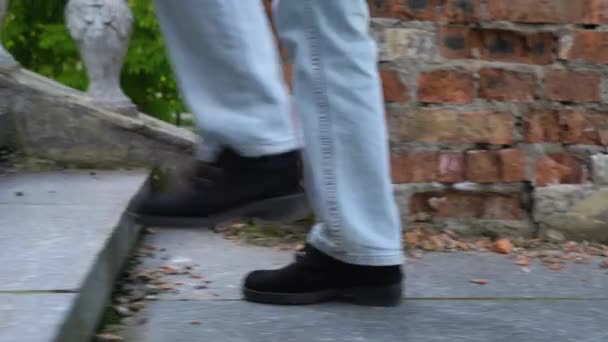 Woman legs in jeans walking on ancient stair side view. Female foot in black suede shoe go up step by step on old classic balustrade. Feet coming and climbing up. Disrupted stairway and stone railings - Footage, Video