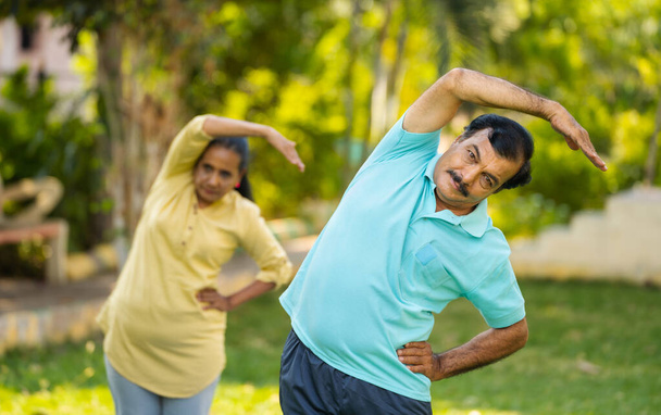 Активная здоровая пожилая пара, занимающаяся йогой или тренировкой в парке - концепция фитнес-тренировок, оздоровления и спокойствия. - Фото, изображение