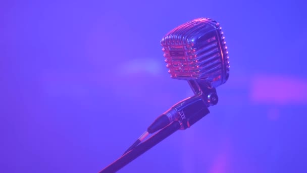 Close-up of a microphone for singing in a karaoke club indoors with a beam of multi-colored spotlights. Professional sound recording microphone, close-up. - Footage, Video