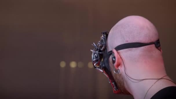 Um homem com uma máscara toca baixo elétrico em um concerto de rock em um clube. Vida nocturna numa cidade grande. Iluminação vermelha e azul - Filmagem, Vídeo