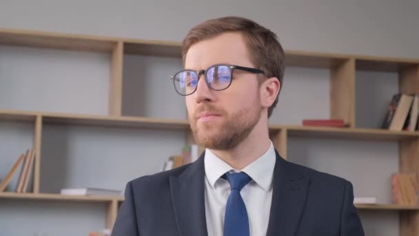 Retrato de um funcionário de escritório usando óculos, ele está olhando para a câmera e sorrindo. Trabalho de um gerente no escritório. Empresários - Filmagem, Vídeo