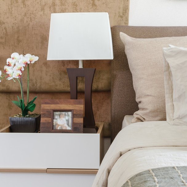 коричневі подушки на ліжку з білою лампою на столі в спальні
 - Фото, зображення