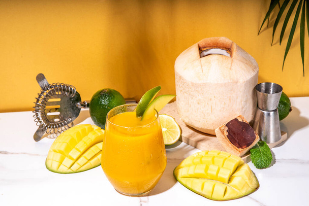 Cocktail margarita à la mangue et à la noix de coco, mocktail non alcoolisé, lassi à la mangue indienne avec de jeunes fruits frais de noix de coco et de mangue, sur fond coloré - Photo, image