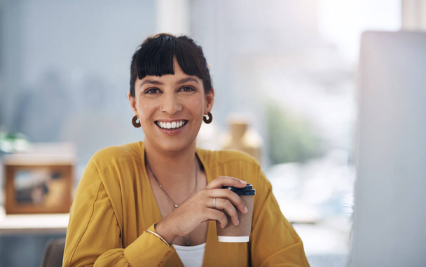I cannot start my day without coffee. Cropped portrait of an attractive young businesswoman sitting alone in her office and holding a cup of coffee - Foto, Imagem