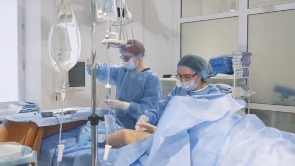 Um flebologista na sala de cirurgia para a clínica cirúrgica de cirurgia vascular venosa realiza uma operação nas pernas para varizes. Técnica inovadora moderna de cirurgia - Filmagem, Vídeo