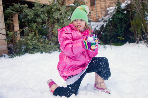 Chica rubia de pie sobre una rodilla con bola de nieve
 - Foto, imagen