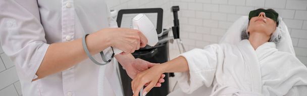 Hair removing procedure of hands. Laser epilation and cosmetology in beauty salon. High quality photo - 写真・画像
