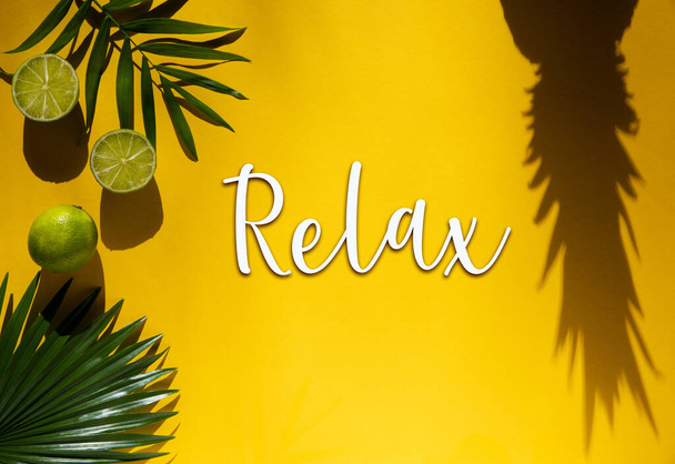 Yellow Flat Lay With English Text Relax. Yellow Summer Background With Tropical Fruits Like Lemon, Pineapple Shadow And Palm Leaf. - Photo, Image