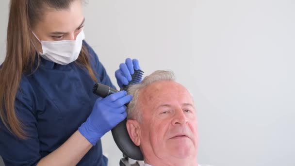 Un hombre mayor está siendo examinado por un tricólogo. El problema de la pérdida de cabello en la vejez. - Imágenes, Vídeo