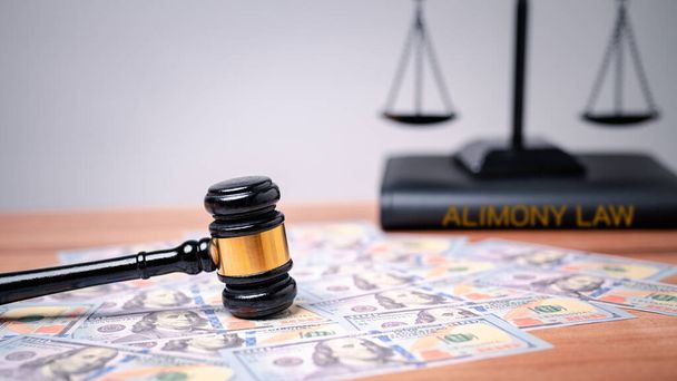 The gavel on a dollar bill in a courtroom represents the complex interplay between alimony law, alimony taxes, financial power, highlighting the need for clear legal frameworks, ethical considerations - Photo, Image