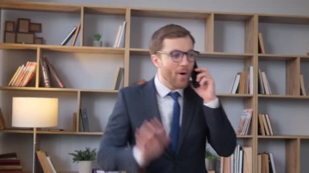 Wütender junger Geschäftsmann, der mitten im Büro mit dem Handy telefoniert. Arbeitsaufwand eines Bankangestellten, Kreditrückstände - Filmmaterial, Video