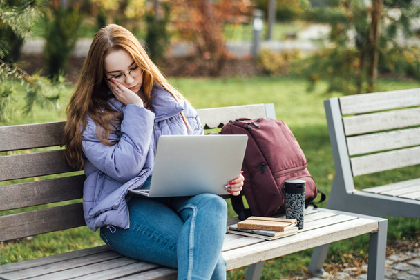 Stressbewältigung in der High School. Gestresste und müde Studentin mit Laptop im Freien. Schwierige Prüfung, Ärger, Fernunterricht - Foto, Bild