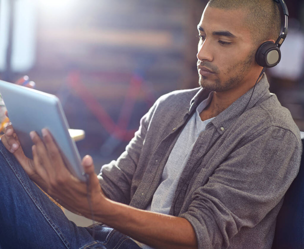 Η μουσική τον παρακινεί. σχεδιαστής που ακούει μουσική σε ψηφιακό tablet σε γραφείο - Φωτογραφία, εικόνα