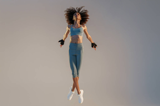 Athletic active woman jumping on studio background. Dynamic movement - Foto, Imagem