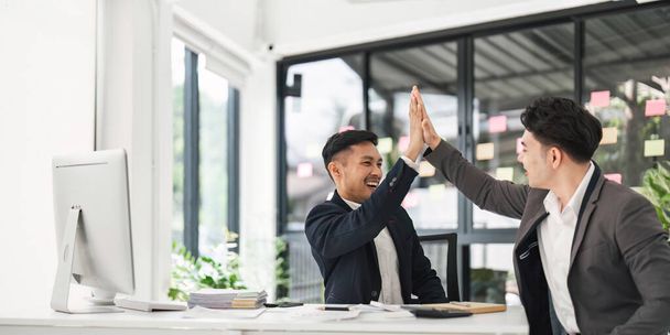 Business people celebrating success in an office. Business team giving a high five to a colleague in meeting.. - Photo, image