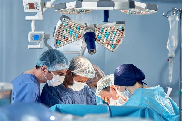 Das Chirurgenteam im Operationssaal beugt sich über den Patienten, komplexe chirurgische Operation, High-Tech-Medizin, Lebensrettung. - Foto, Bild