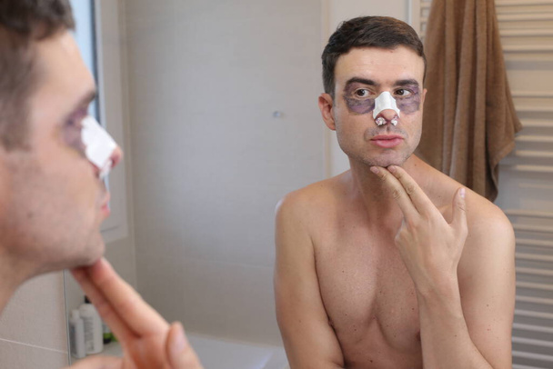 portrait of handsome young man after facial plastic surgery in front of mirror - Фото, зображення