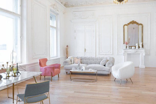 very light baroque style luxury interior of big sitting room. White walls decorated with awesome stucco. Royal style apartment with chic furniture with gold elements - Foto, Imagen
