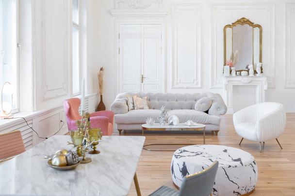 very light baroque style luxury interior of big sitting room. White walls decorated with awesome stucco. Royal style apartment with chic furniture with gold elements - 写真・画像