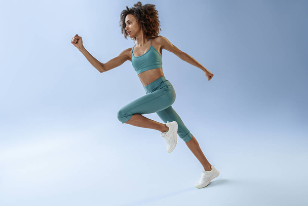 Athletic active woman jumping on studio background. Dynamic movement - Photo, image