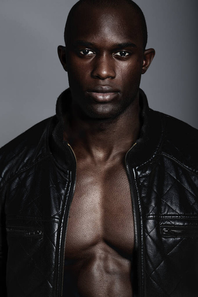 Fashion, portrait and black man in leather jacket in studio isolated on a gray background. African male model, serious face and coat, confidence and stylish clothes or trendy outfit from Nigeria - Valokuva, kuva