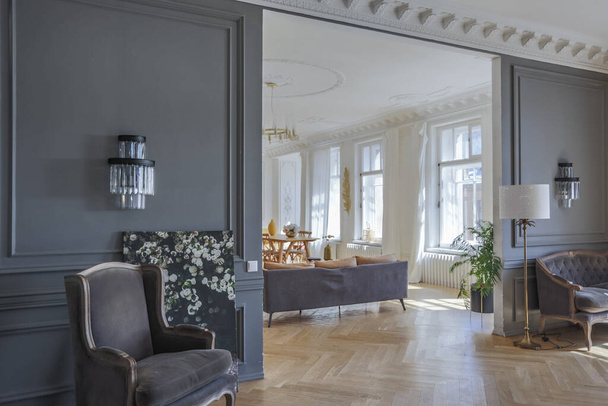 luxury interior of a spacious apartment in an old 19th century historical house with modern furniture. high ceiling and walls are decorated with stucco - Foto, afbeelding