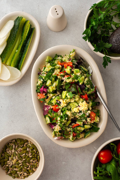 Gezonde lunch, gierstpap of quinoa met gemengde salade, tomaten en komkommers met peterselie en pompoenpitten, gezond eten, bovenaanzicht - Foto, afbeelding