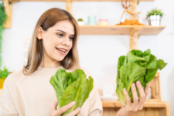 Young woman preparing healthy food with salad vegetables. woman sitting at pantry in a beautiful interior kitchen. The clean diet food from local products and ingredients Market fresh. - Photo, Image